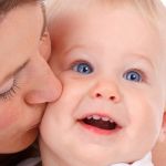 Mutter küsst liebevoll ihr Baby auf die Wange 