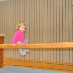 Kleines Mädchen turnt an einem Holzbalken