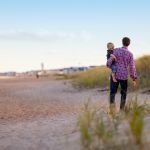 Vater hat sein Kind auf dem Arm, Rückansicht