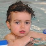 Ein Junge mit Schwimmhilfen im Wasser