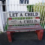 Eine Holzbank mit der Aufschrift "Let a child be a child"