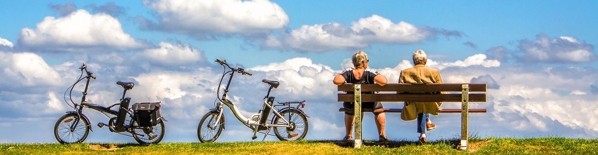 Ein Mann und eine Frau sitzen auf einer Bank, neben ihnen stehen zwei Fahrräder