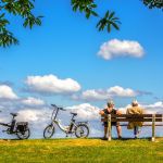 Ein Mann und eine Frau sitzen auf einer Bank, neben ihnen stehen zwei Fahrräder